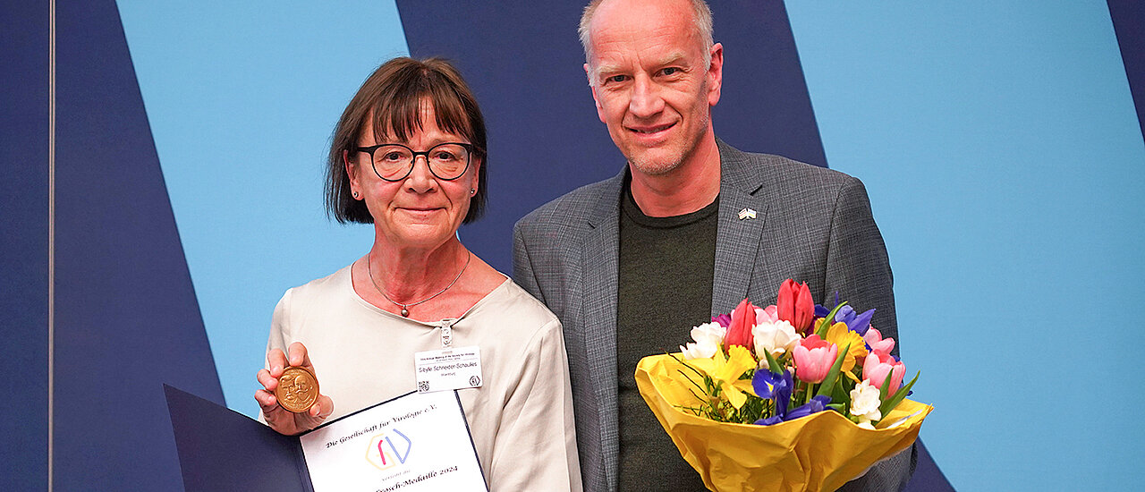 Sibylle Schneider-Schaulies 2024 beim Kongress in Wien mit der Loeffler-Frosch-Medaille und ihrem Laudator Ulf Dittmer. (Bild: Volker Lohmann)