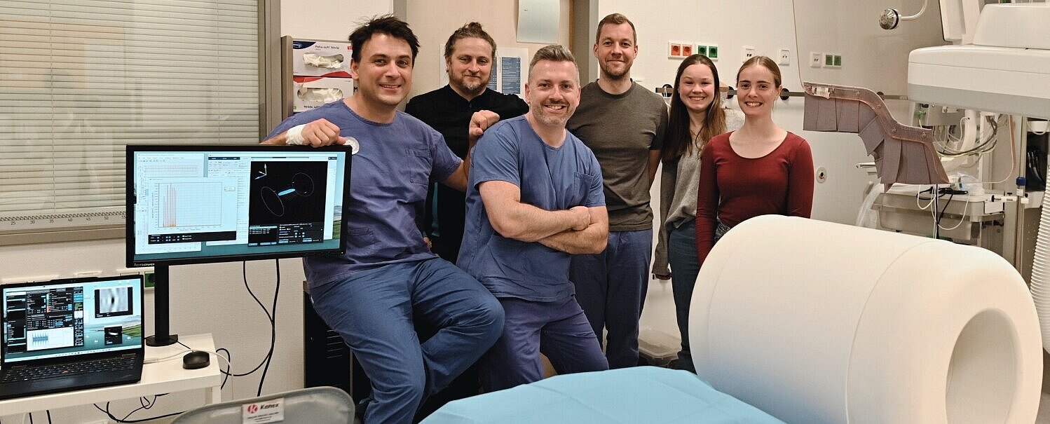 Das Team freut sich über die gelungene erste MPI-Bildgebung am Menschen und steht glücklich hinter dem Scanner.