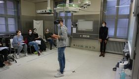 Virtual-Reality-Seminar an der Uni Würzburg mit VR-Brille. Studierende verfolgen den Fall auf einer Leinwand mit.