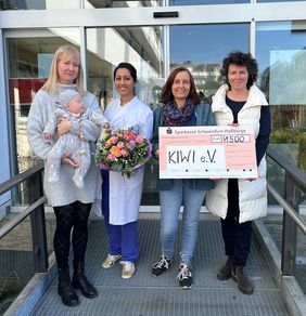 Gruppenfoto bei der Spendenübergabe an der Universitäts-Kinderklinik Würzburg. Tamara Kirtz unterstützt den Aufbau einer Frauenmilchbank am UKW mit 1.500 Euro. Zu sehen ist: von links: Tamara Kirtz mit Sohn Max, Dr. Pia Paul (Oberärztin Kinderklinik UKW), Natalie Seeberger (Pflegekraft und Stillberaterin UKW) und Ina Schmolke (Erste Vorsitzende KIWI e.V.). © Annika Wolf / UKW