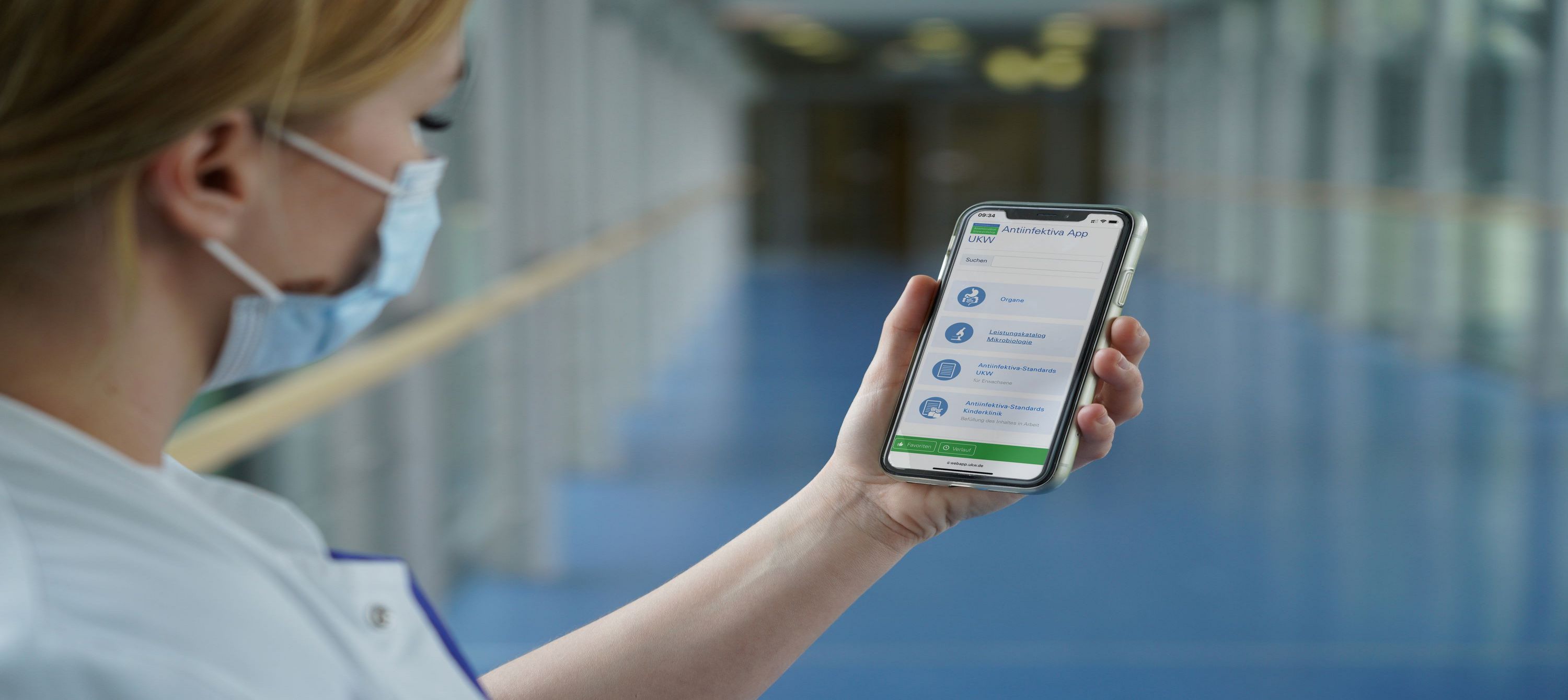 Eine Pflegekraft hält ein Smartphone mit der Antiinfektiva-App in der Hand. 