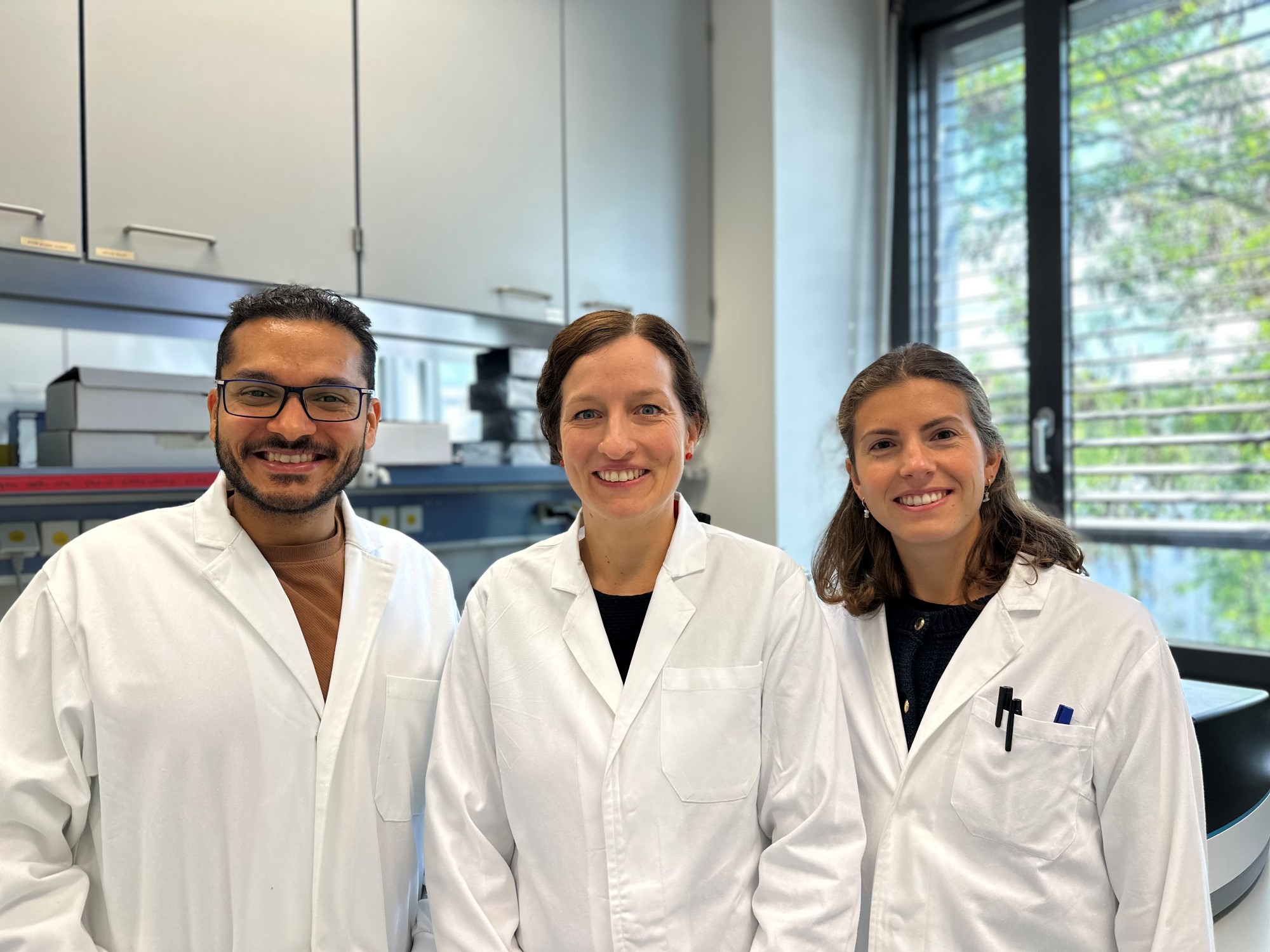 Riedel und Erstautoren Angela Riedel Studienteam: Angela Riedel, Moutaz Helal und Greta Mattavelli im stehen in weißen Kitteln im Labor.